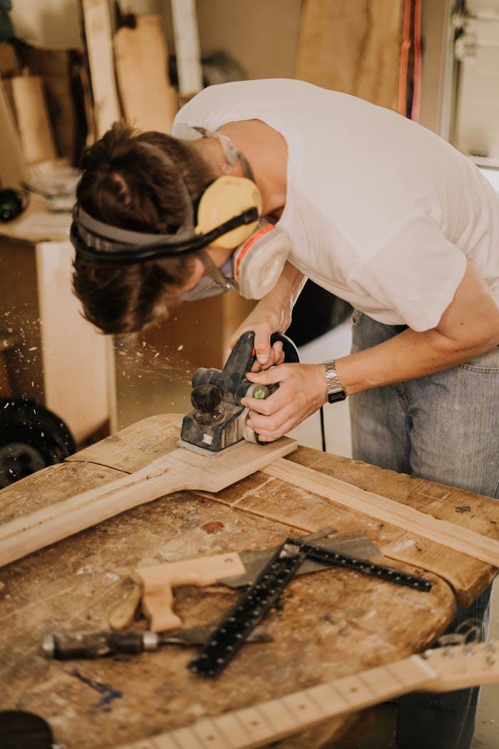 Skilled artisan sanding a guitar neck for handmade electric guitar in a cozy workshop.
